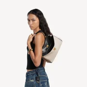 Bolsa em lona de linho bege natural e pele de cordeiro curtida vegetalmente na cor preta, com detalhes metálicos em tom de ouro envelhecido