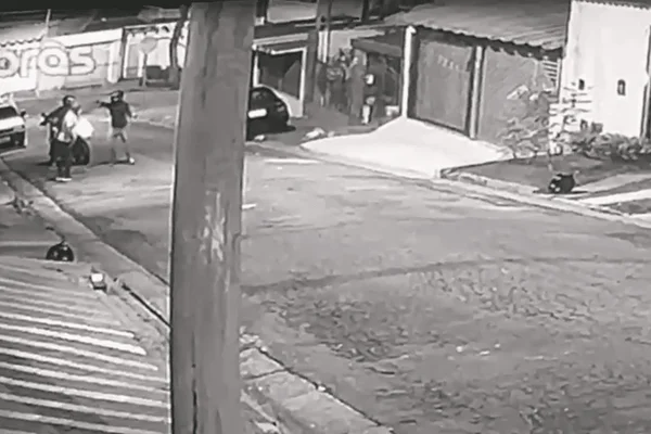Imagem em preto e branco de um homem sendo assaltado por dois indivíduos em uma moto - Metrópoles