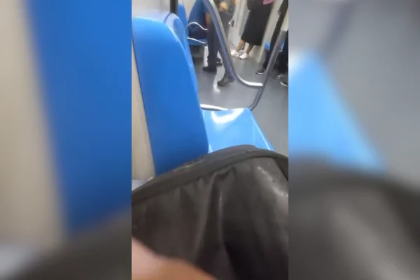 Imagem colorida do interior de um trem com bancos azuis e pessoas sentadas e em pé - Metrópoles
