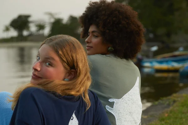 Mulheres sentadas no chão usando camisetas com estampa nas costas - Metrópoles