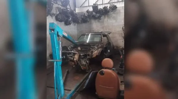 foto mostra um carro roubado sendo desmanchado por criminosos em uma oficina