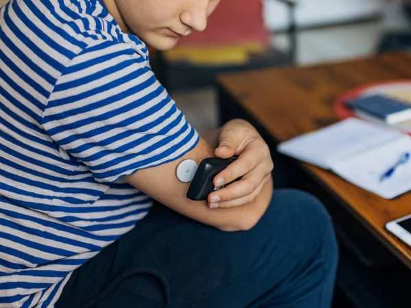 Menino com doença crônica e diabetes tipo 1 usa um dispositivo de leitura, um monitor contínuo de glicose, sobre um sensor de glicose no sangue para ler o nível de açúcar no sangue e saber quando é hora de tomar uma dose de insulina. Imagem ilustrativa - Metrópoles - glicemia
