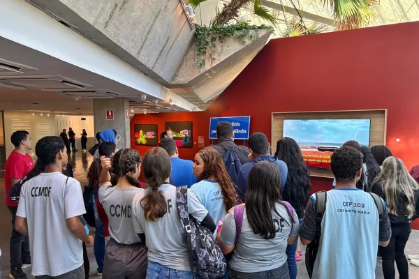 Foto colorida mostra estudantes na exposição
