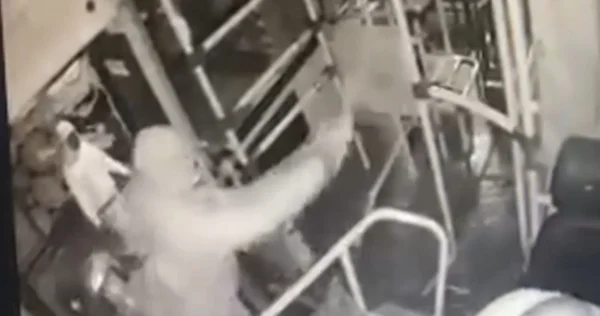 Imagem preta e branca e homem com capuz despejando gasolina em cabine de ônibus - Metrópoles