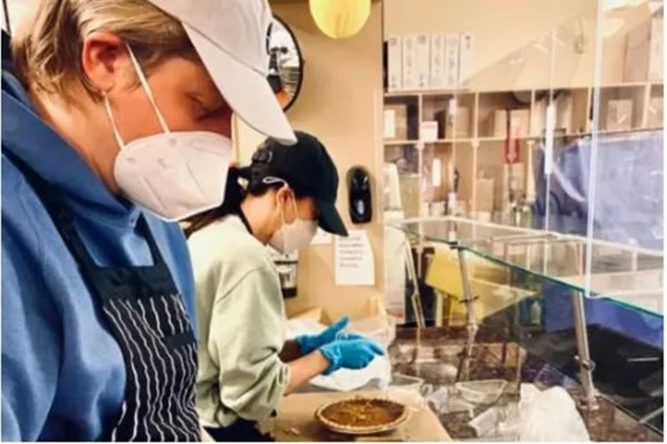 Foto colorida de duas mulheres brancas usando mascara em boné