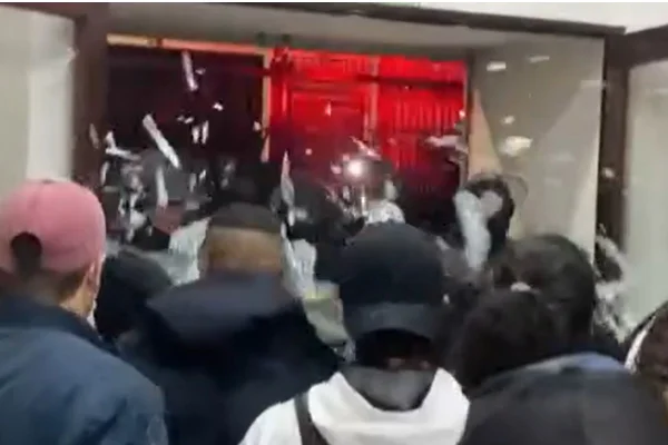 Estilhaços de vidro voando em direção a grupo de pessoas após a PM forçar entrada em uma ocupação de prédio no centro de São Paulo. - Metrópoles