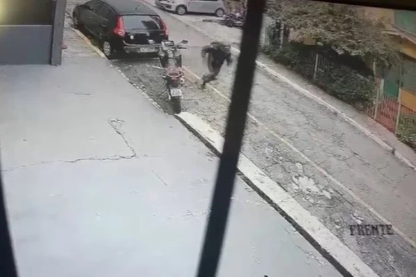 Imagem colorida mostra homem vestido com capacete correndo ao lado de moto após trocar tiros com PM de folga na Vila Mariana - Metrópoles