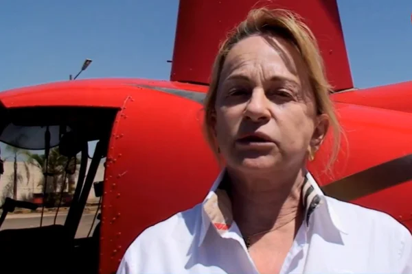 Imagem colorida mostra deputada Magda Moffato em frente a helicóptero vermelho - Metrópoles
