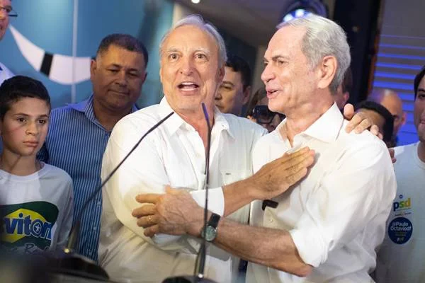 Fotografia colorida de dois homens se abraçando em palco