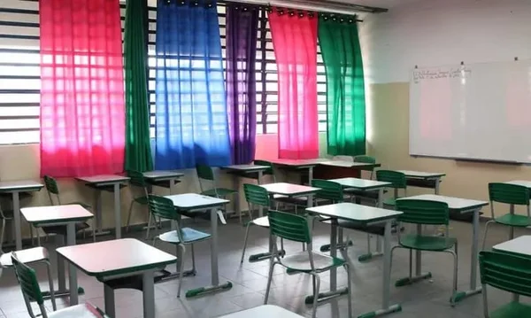 Imagem mostra sala de aula vazia com cadeiras verdes. As cortinas das salas são rosas, verdes, azuis e roxas - Metrópoles