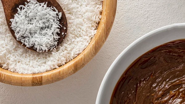 Foto colorida mostra recipiente com coco ralado e outro com chocolate