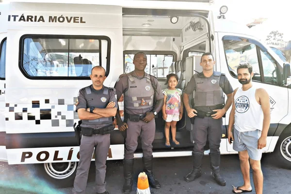 Imagem colorida de três policias em pé em frente a uma unidade móvel da PM - Metrópoles