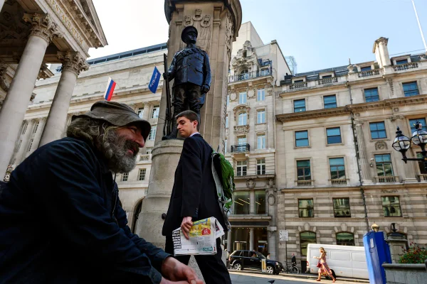 Um trabalhador de paletó e gravata no distrito financeiro de Londres, frequentemente chamado de The City, lança um olhar de desdém para um morador de rua em frente à Royal Exchange, fundada em 1565 como centro comercial de Londres. Metrópoles