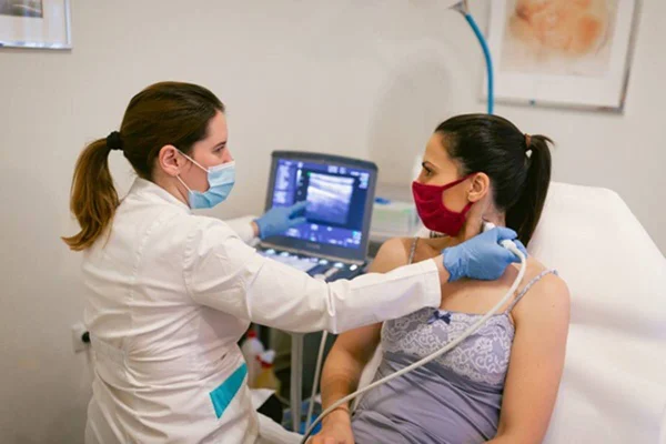 Foto colorida de médica examinando pescoço de paciente