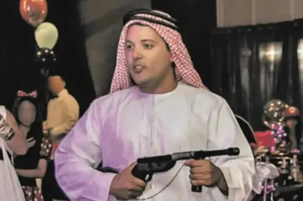Homem com roupas tradicionais de países árabes porta uma arma em uma festa - Metrópoles