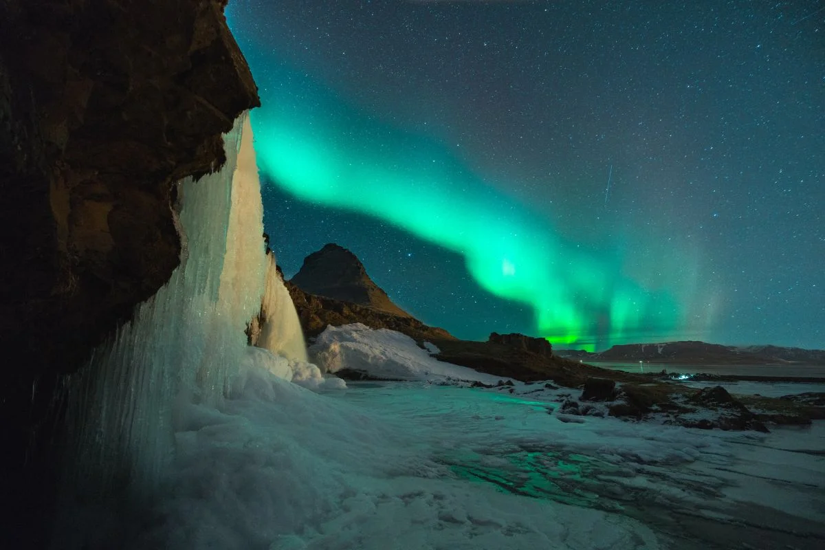 Montanha Kirkjufell e a cachoeira Kirkjufellsfoss iluminadas pela aurora boreal verde na Islândia Montanha Kirkjufell e a cachoeira Kirkjufellsfoss iluminadas pela aurora boreal verde na Islândia