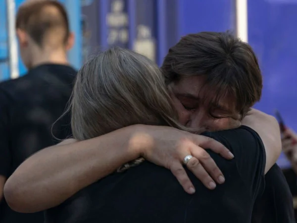 Foto colorida de mulheres se abraçando e chorando perto de um trem de evacuação na estação ferroviária de Pokrovsk - Metrópoles