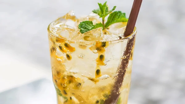 Foto colorida de copo com drink de maracujá