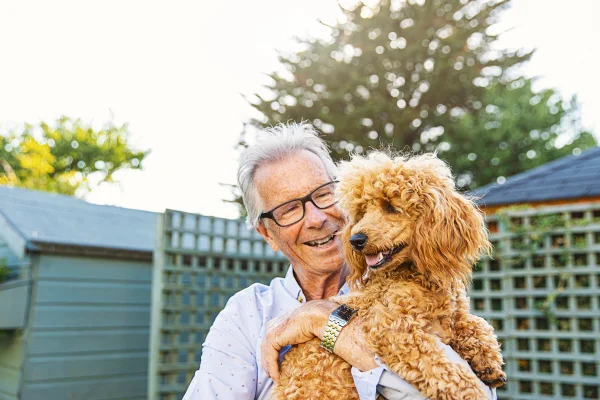 Imagem colorida de idoso segurando cachorro no colo - Metrópoles