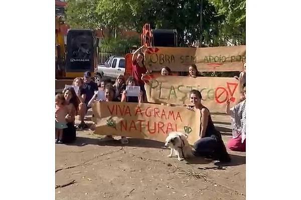 Pessoas posam para foto com cartazes defendendo grama natural