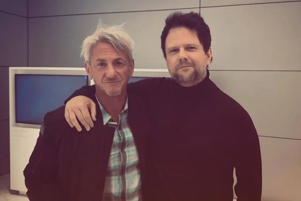 Imagem colorida de Selton Mello e Sean Penn abraçados - Metrópoles