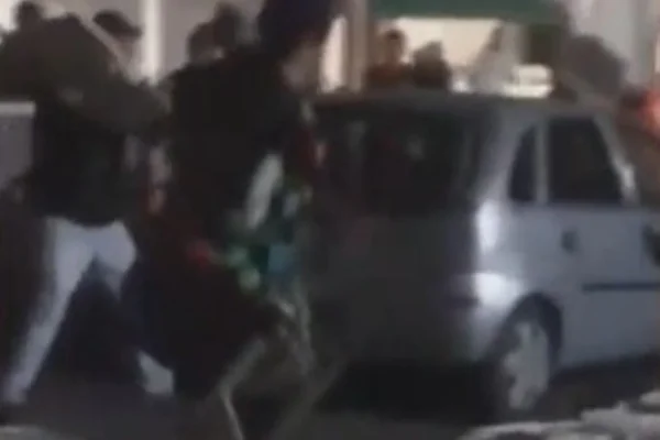 Imagem colorida de carro sendo alvejado por cadeiradas. Metrópoles