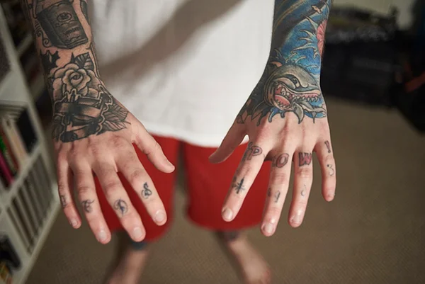 Foto colorida de braços de homem com tatuagem - Metrópoles