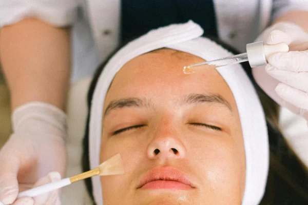 Mãos aplicando óleo em rosto de mulher - Metrópoles