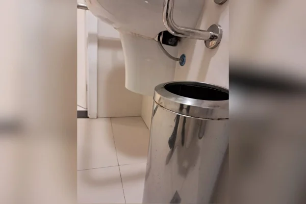 Foto colorida de celular instalado embaixo de pia de banheiro feminino de prédio comercial de Santos, no litoral de São Paulo.