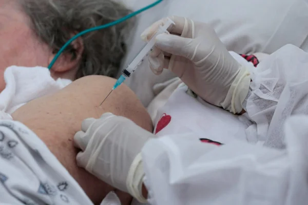Idosa acamada recebe vacina contra a covid-19 em Goiânia