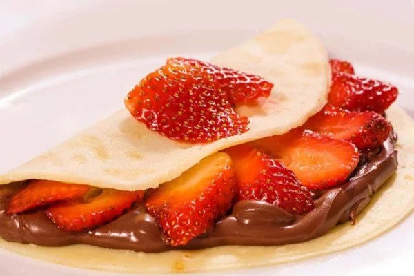 Foto colorida de um crepe de nutella com morangos