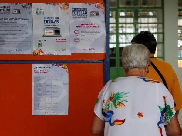 foto colorida de movimento em escola municipal de SP para eleição do Conselho Tutelar da cidade; no detalhes, pessoas chegam à escola em meio a cartazes sobre a eleição - Metrópoles