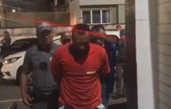 Foto colorida de homem de camisa vermelha sendo preso por policial militar - Metrópoles