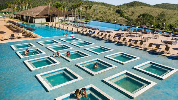 Fotografia colorida mostrando várias piscinas com famílias dentro-Metrópoles