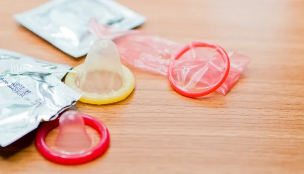 Preservativos de cores variadas abertos em cima de uma mesa