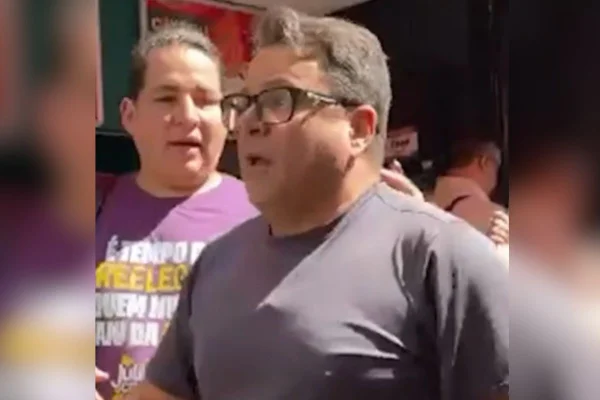 Imagens coloridas mostram homem branco, cabelos curtos, usando óculos, camiseta cinza e acima do peso, discutindo com pessoas durante caminhada de campanha eleitoral em SP