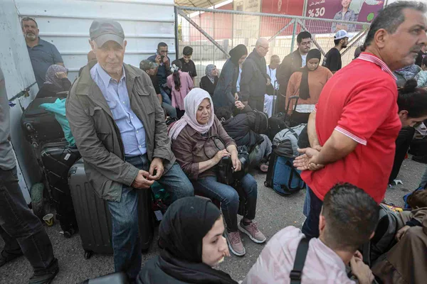 Estrangeiros esperam no Portão Fronteiriço de Rafah para cruzar o Egito