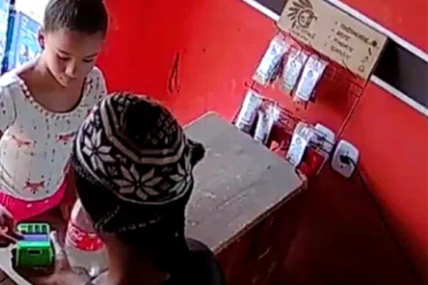 Imagem colorida de menina parda, com cabelo preso em coque, em balcão de venda - Metrópoles