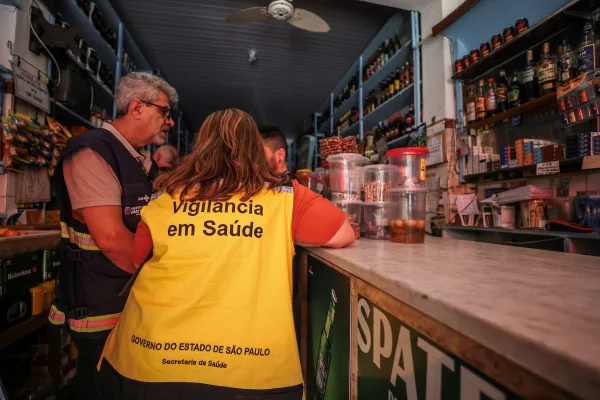 Imagem colorida de funcionária da Vigilância Sanitária de costas durante interdição por suspeita de metanol - Metrópoles