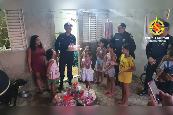 Pm com bolo e meninas ao redor