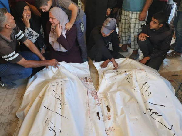 Mulher e homens choram ao lado de corpos embalados por lençóis em Gaza