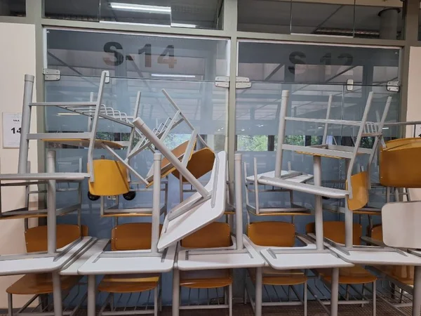imagem colorida mostra carteiras empilhadas em frente às portas de duas salas de aula na faculdade de engenharia da usp - metrópoles
