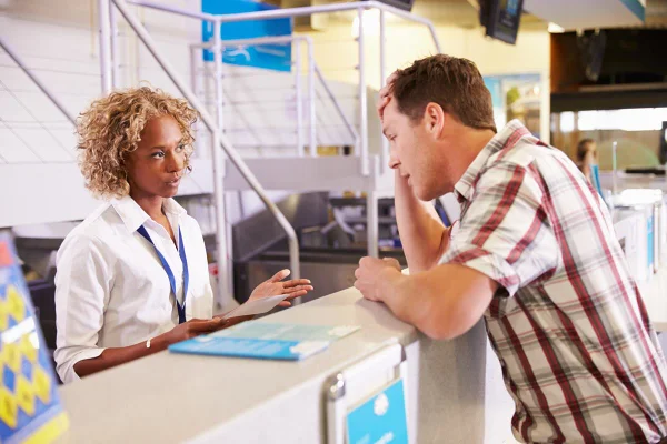 Homem reclamando com atendente em check-in de aeroporto - Metrópoles