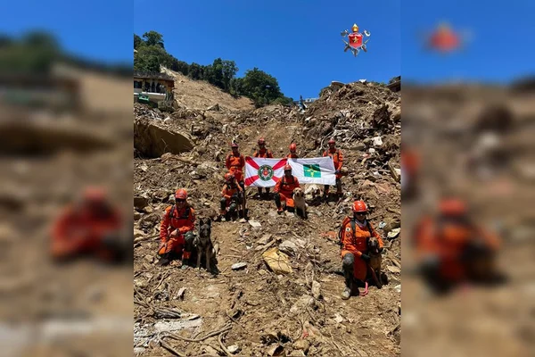 Bombeiros segurando bandeira em morro de terra