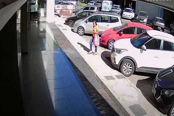 mulher de blusa amarela caminhando em estacionamento de prédio residencial