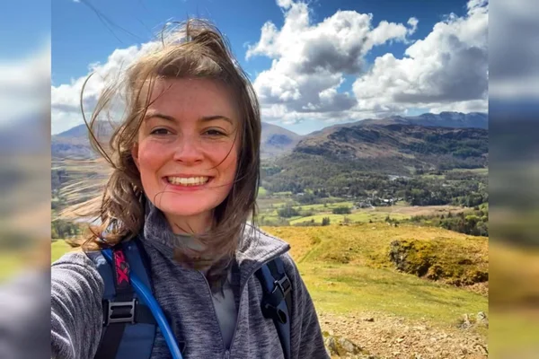 Foto mostra mulher branca e jovem sorrindo para a câmera em dia ensolarado - Metrópoles - coceira, fígado