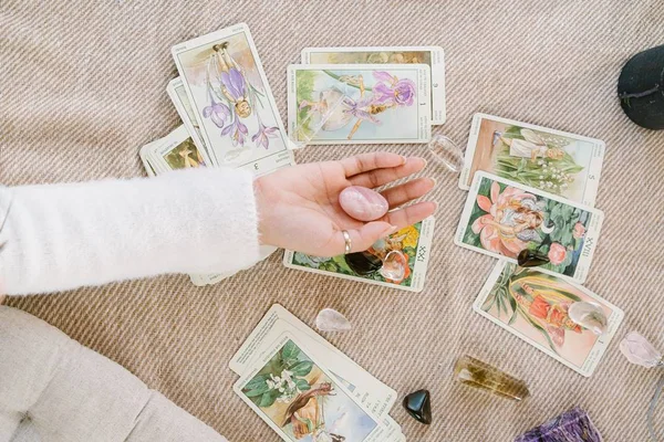 Mulher com cristal na mão e cartas de tarô no chão - Metrópoles