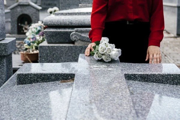 Mulher coloca flores sobre túmulo em cemitério - Metrópoles