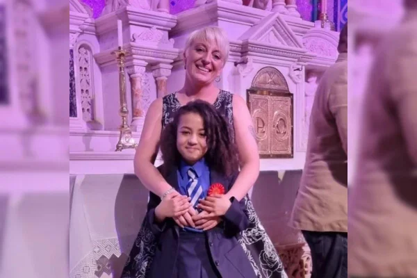 Imagem colorida de mãe e filha abaraçadas com luz rosa no fundo - MEtrópoles