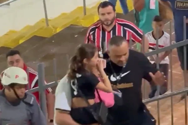 Imagem colorida de garota sendo levada no colo - Metrópoles